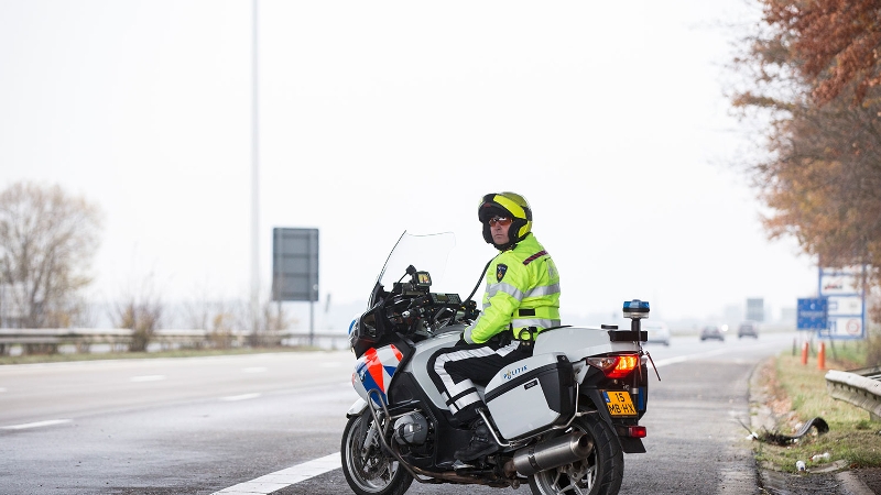 motoragent staat langs een snelweg