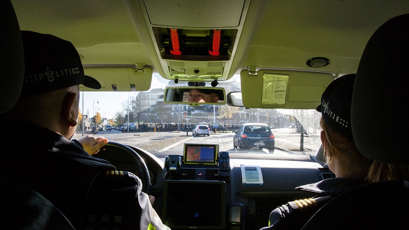 twee agenten in dienstauto kijken uit op de weg voor hen