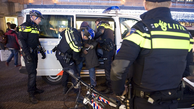 arrestant wordt afgevoerd in politiebus